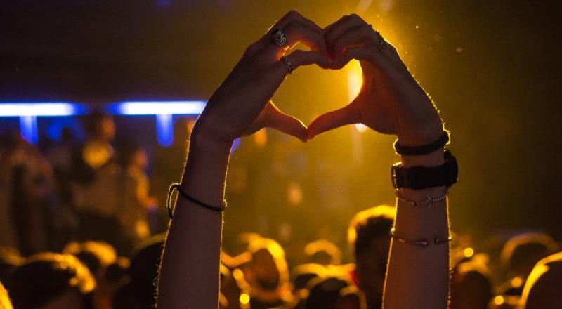 Hands in heart shape at a concert discovered via event booking websites